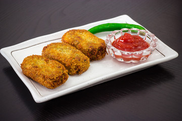 Spicy golden fried crisp cutlets served tomato sauce or ketchup on white plate, prepare for iftar Ramadan. Selective focus