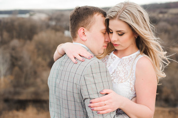Portret of happy young couple hugging on the edge of the mountain