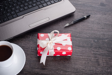 Laptop computer with cup of tea and gift box