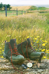 Hiking boots with knife and compass on log in field