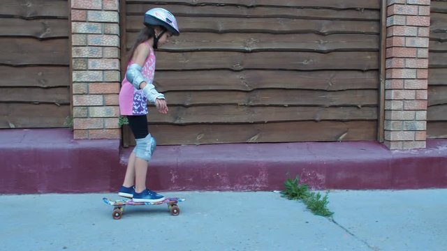 Little girl skating on skateboard. Girl on a scooter in a helmet.