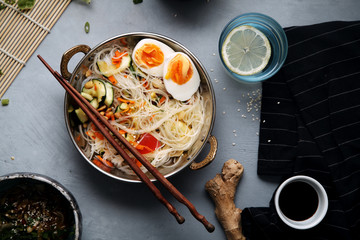 Spicy veggie wok: rice noodles with zucchini, onion and carrot. Asian styled lunch on rustic background. Composition with copy space for text