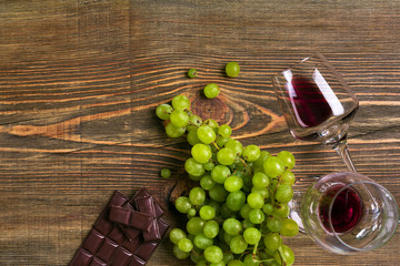 Two glasses of red wine, green grapes and chocolate, top view