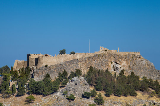 Acropolis on a hill in the city of Lindos. Fragment of residential buildings at the foot of the mountain.