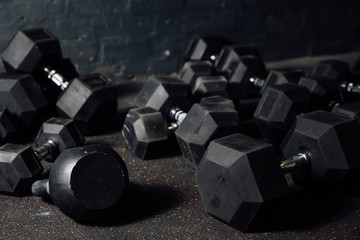 Many dumbbells lie randomly on the floor. Loft gym. Place for the text.