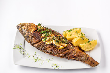 Grilled carp fish with rosemary potatoes and lemon, close up