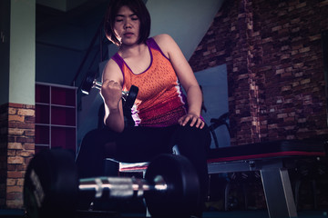 Fototapeta na wymiar Young woman exercising with weights in the gym. Fit girl with dumbbell. Sport and fitness concept
