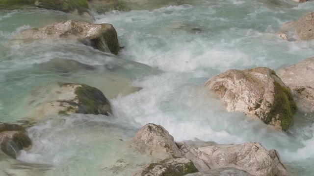 Turquoise water flows between white moss-grown stones in a beautiful forest in Slovenia_realtime_4k. Lepenica river, Slovenia. Spring of 17'