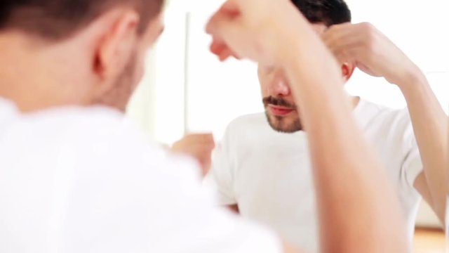happy man applying hair styler at bathroom