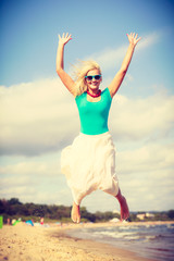 Obraz premium Blonde woman wearing dress playing jumping on beach
