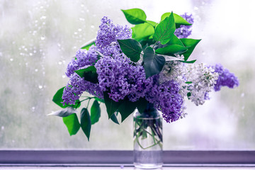 Bouquet of lilac on the rainy window