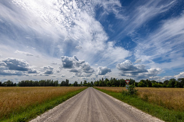 romantic gravel road in country under blue sky