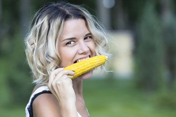 The girl is eating boiled sweet corn in the park 