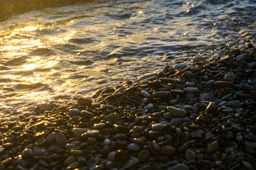 sea pebble beach with multicoloured stones, waves with foam