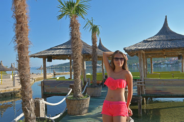 Girl in pink bikini standing in front of beach bar