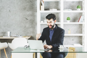 Naklejka premium Happy businessman using laptop at workplace