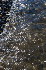sea pebble beach with multicoloured stones, waves with foam