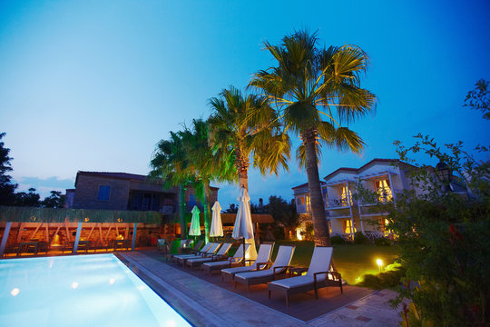 Evening view of cozy small Mediterranean boutique hotel pool with chaise-longue, relaxing