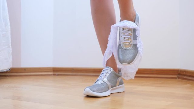 A sexy woman in silvery sneakers takes off her panties. 4k. Slow motion.