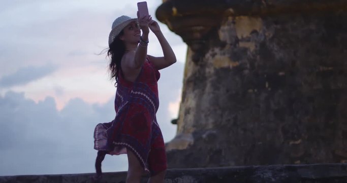 Slow motion of woman taking selfies of herself by fortress during sunset