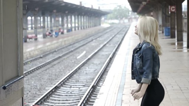 Excited young woman waiting for her boyfriend arrival in railway train platform station