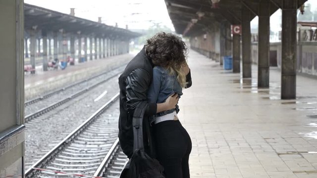 Young couple embracing and saying goodbye before boyfriend getting on train to leaving