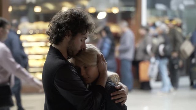 Blonde beautiful girl kissing hugging and talking with her boyfriend in public center using caressing and romantic gesture