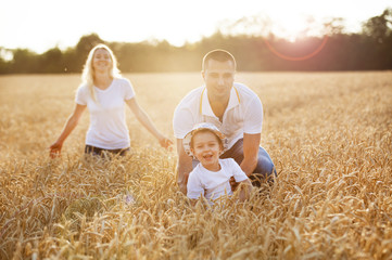 Happy family playing with a child in a wheat field