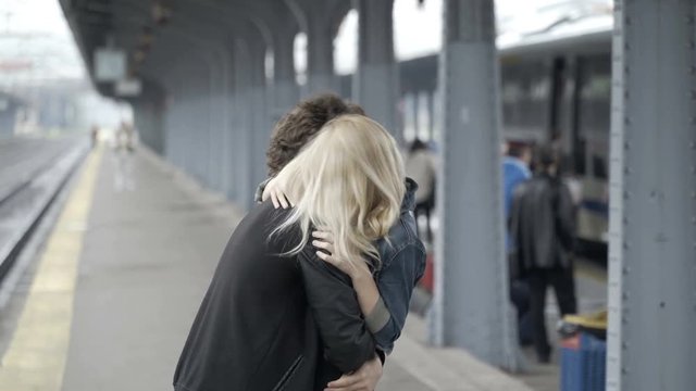 Teenage couple in love tickling and kissing in train station having fun before departure waiting the train