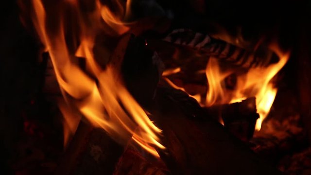 Closeup of beautiful burning bright fire in fireplace in darkness. Real time full hd video footage.