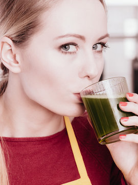 Woman in kitchen holding vegetable smoothie juice