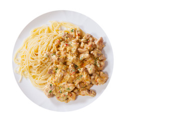 Sliced fried chicken meat in a creamy sauce with spaghetti pasta in a plate. top view. isolated on white