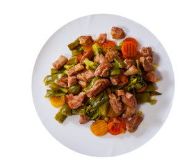 stewed meat with vegetables in a plate. top view. isolated on white