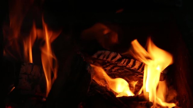 Closeup of bright burning fire in fireplace in darkness. Real time full hd video footage.