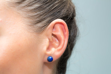 Ear of girl with blue earring