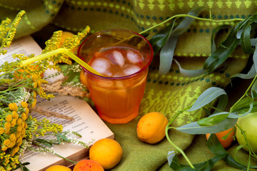 a glass of apricot juice with ice and a book