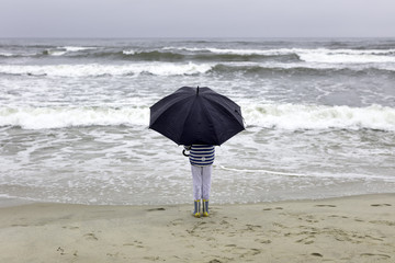 Dziecko na plaży w czasie deszczu - obrazy, fototapety, plakaty