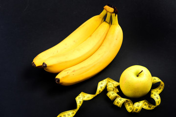 Bananas and untwisted measuring tape around green apple