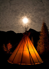 Illuminated teepee under the full moon.