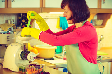 Woman make vegetables juice in juicer machine