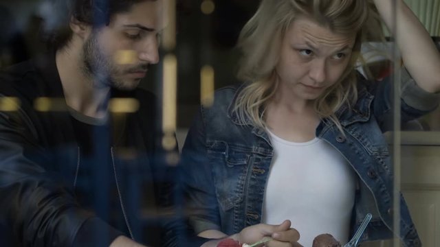 Teenage couple enjoying their first date talking and eating ice cream into a coffee shop pub