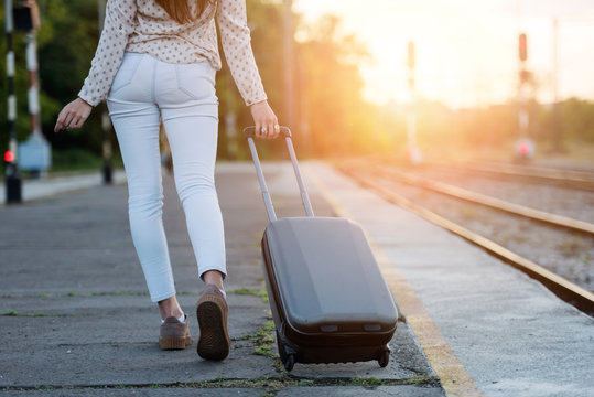 Young woman with luggage on train station in sunset