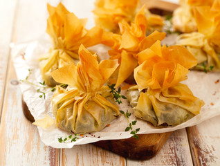 Spinach and Feta phyllo purses on a wooden rustic table, delicious vegetarian appetizers 