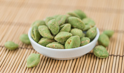 Portion of Wasabi coated Peanuts on wooden background (selective focus)