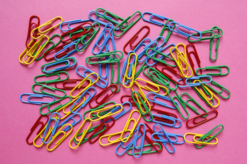 colorful office paper clips on pink background