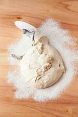 Kneading dough with a kitchen robot. Dough on a wooden table sprinkled with flour
