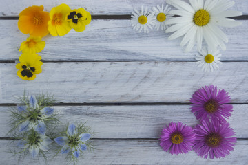 Frame of summer flowers on a light wooden surface 2