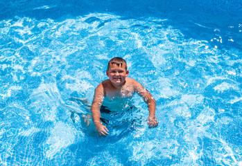 Young boy kid child eight years old splashing in swimming pool having fun