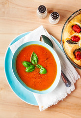 Traditional cream of tomato soup with basil on wooden table