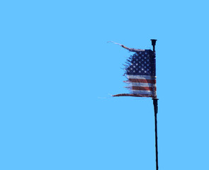 old worn USA flag waving on the pole in blue sky